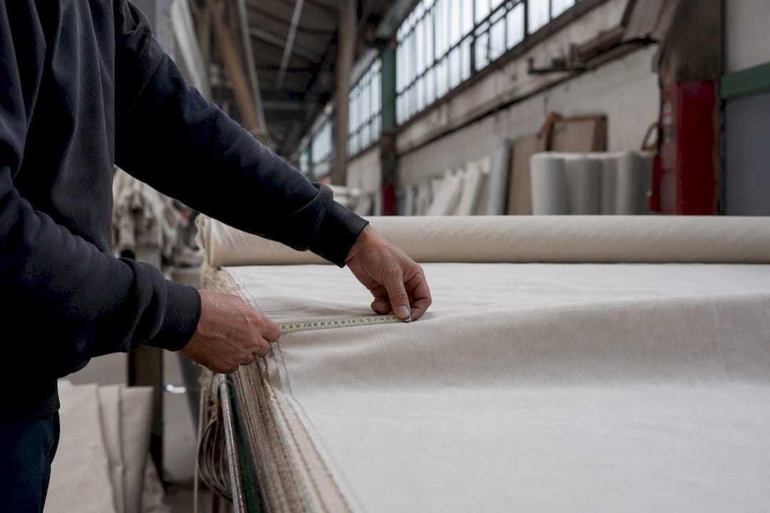 Manos midiendo un rollo de tela en una fábrica textil